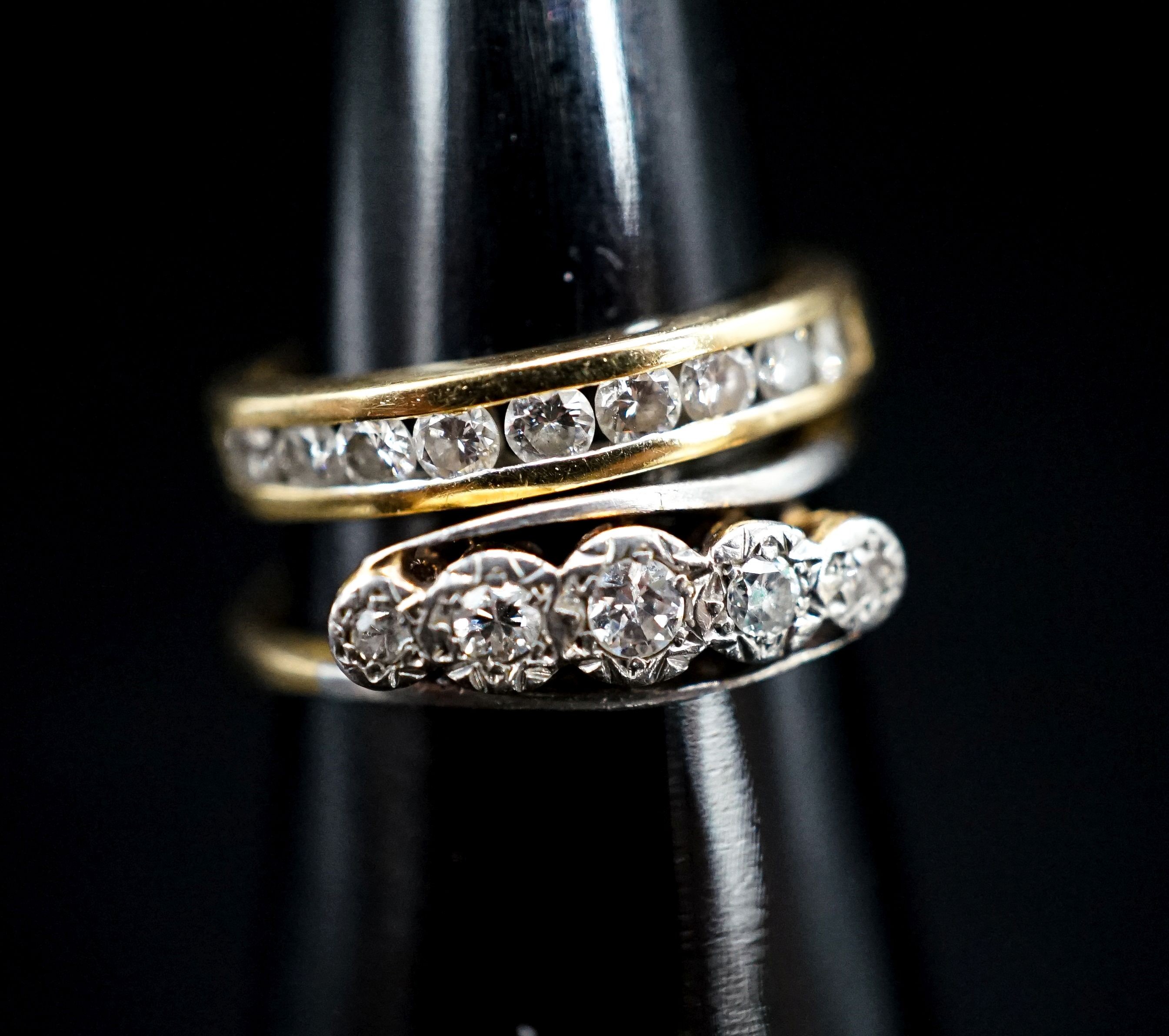 A 750 yellow metal and channel set nine stone diamond ring, size G, gross 2.6 grams and an early 20th century yellow metal and illusion set five stone diamond crossover ring, gross 2 grams.